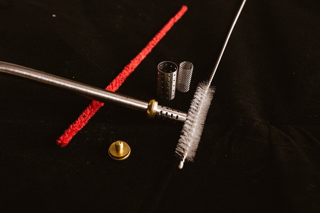 Disassembled firearm cleaning tools with a rod, brush, and red bore snake