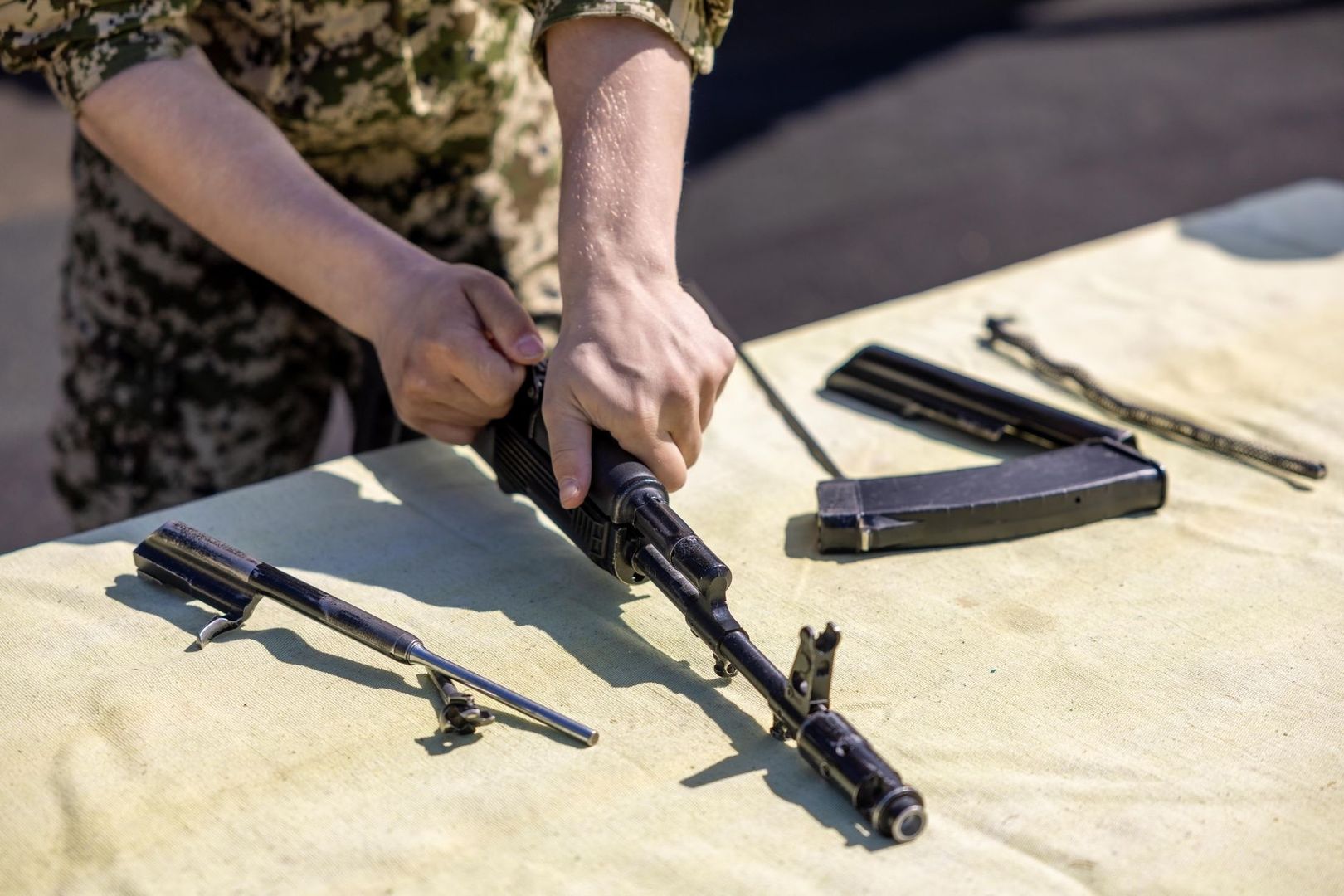 Person inspecting a disassembled rifle on a workbench