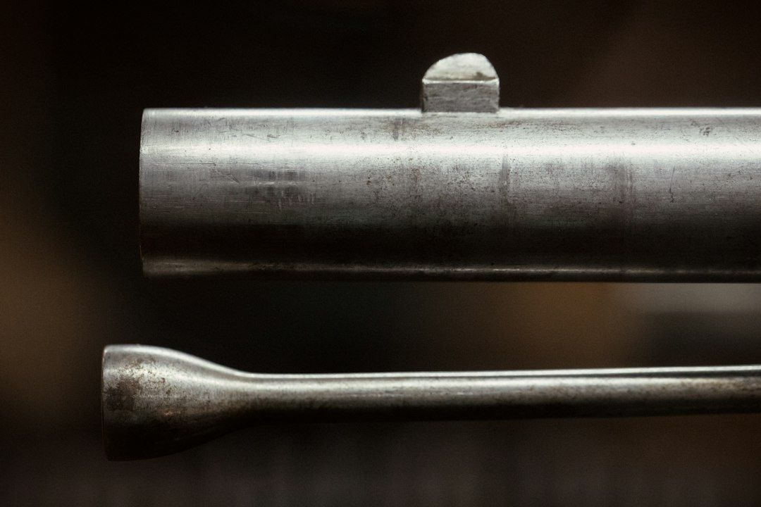 Close-up of two worn metal rods displayed against a dark background